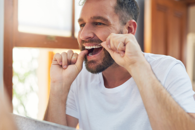 Invisalign patient using a water flosser on their teeth