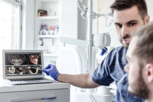 Dentist and patient reviewing scans on computer screen